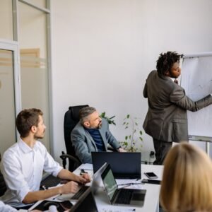 A diverse team in a modern office engaged in a strategic business meeting led by a presenter.
